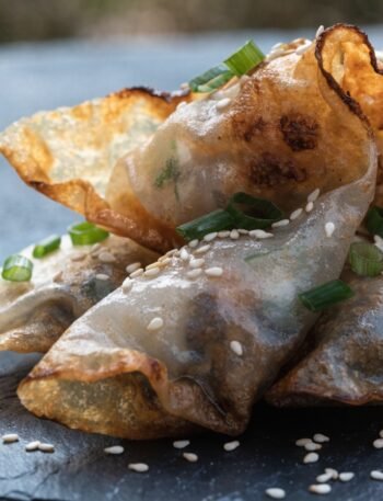 crispy fried rice paper dumplings recipe hero presentation - Stunning photorealistic hero shot of crispy fried rice paper dumplings arranged on a dark slate plat