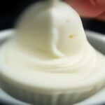 How to Store Buttercream Without Losing Texture cooking process - Macro photograph of a stand mixer paddle attachment mixing creamy buttercream, capturing air pockets