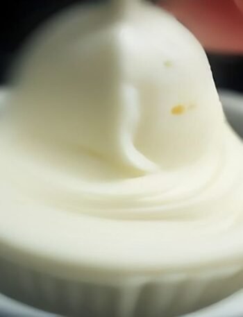 How to Store Buttercream Without Losing Texture cooking process - Macro photograph of a stand mixer paddle attachment mixing creamy buttercream, capturing air pockets