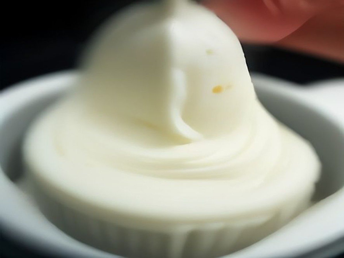 How to Store Buttercream Without Losing Texture cooking process - Macro photograph of a stand mixer paddle attachment mixing creamy buttercream, capturing air pockets