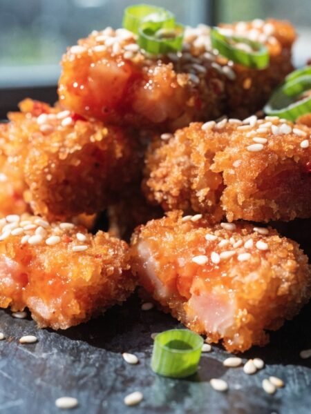 spicy crunch tuna crispy rice bites - Stunning photorealistic hero shot of spicy crunch tuna crispy rice bites on a dark slate plate, garnished with sliced gr