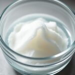 Can I use gelatin to fix an unbaked runny cheesecake? recipe hero presentation - A close-up overhead shot of unflavored gelatin powder blooming in a small glass bowl with cold water