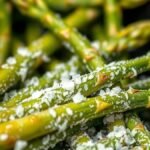 Do you need to thaw frozen asparagus before air frying? recipe hero presentation - Close up food photography of frozen green asparagus spears coated in glistening oil and sea salt ins