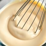 How long does it take to prepare runny no bake cheesecake filling? recipe hero presentation - Close up of smooth no bake cheesecake filling in a glass bowl with a whisk