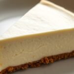What is the secret to perfect runny no bake cheesecake filling? recipe hero presentation - A photorealistic close-up of a creamy no-bake cheesecake slice on a white ceramic plate, showing a s